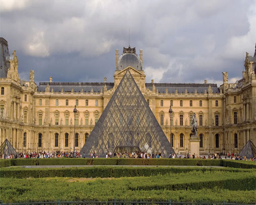 image of the Louvre Museum at day, with a spotlight illuminating a specific detail on the facade, such as a sculpture, inscription, or architectural element. The image suggests that the detail might hold a hidden clue or message.