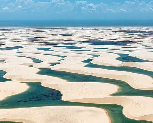 Fresh water collecting in the valleys between sand dunes in the Lençóis Maranhenses National Park in Brazil. A layer of rock beneath the sand prevents the rain water from dissipating during the rainy season, resulting in a broad expanse of lagoons.
