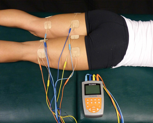 Athlète en convalescence avec un appareil de stimulation musculaire électrique à quatre canaux attaché à ses ischio-jambiers à l’aide de coussinets auto-adhésifs
