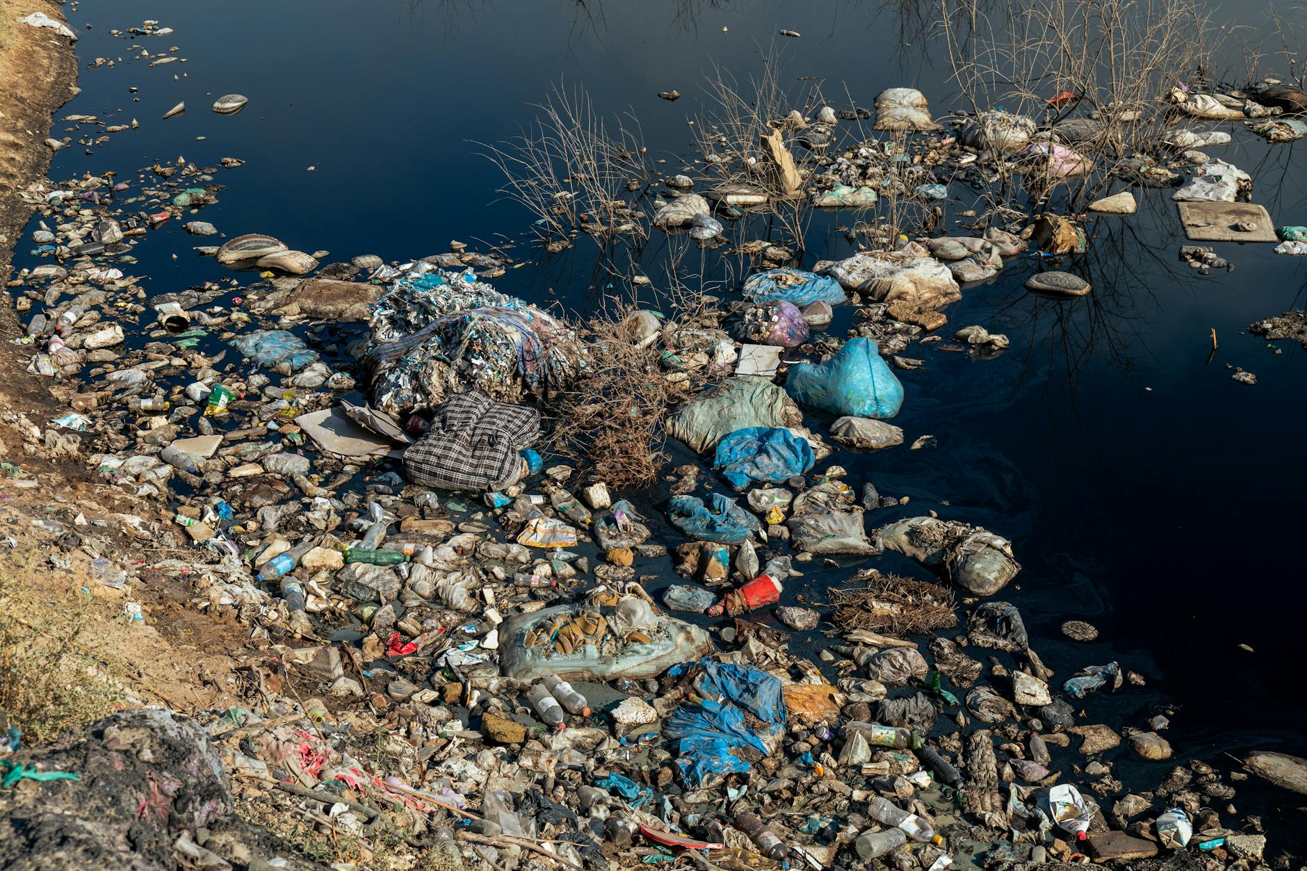 Residuos plásticos en la orilla de un río