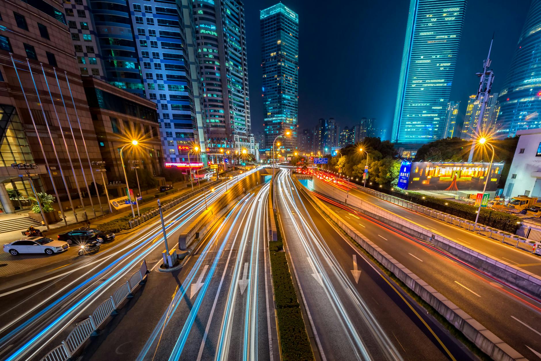 Fotografía de lapso de tiempo de un vehículo en una carretera de concreto cerca de un edificio de gran altura durante la noche