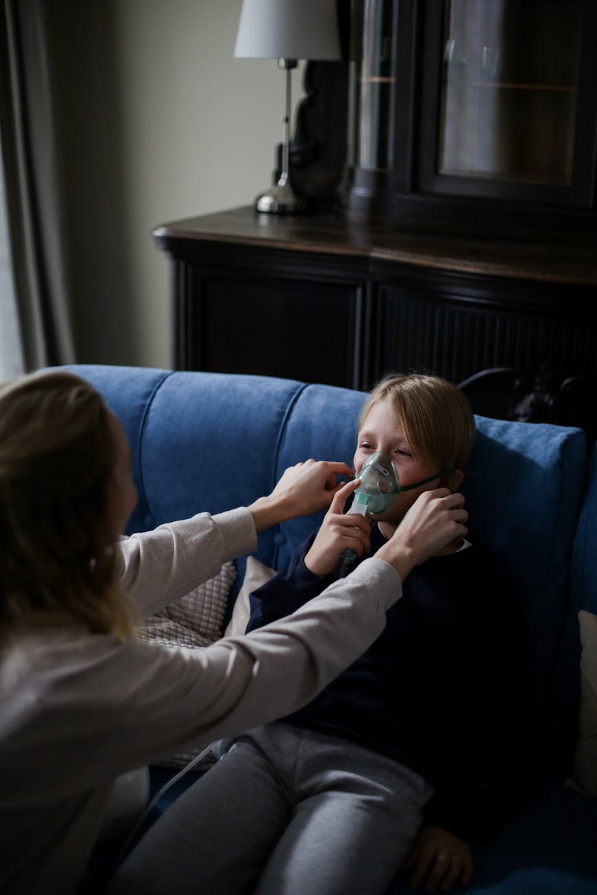 un niño enfermo en mangas largas azules sentado en el sofá