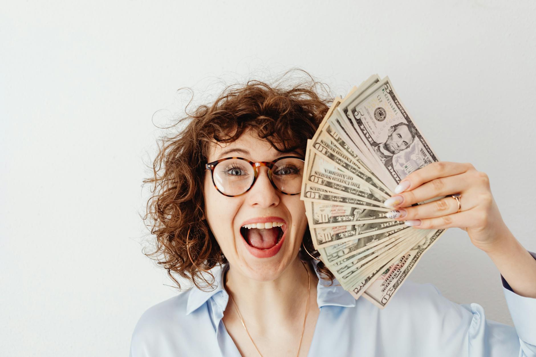 Mujer feliz en blusa azul de manga larga sosteniendo dinero