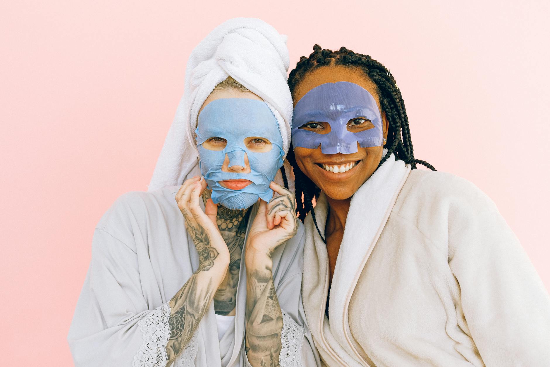 smiling multiethnic girlfriends in collagen cosmetic masks after taking bath